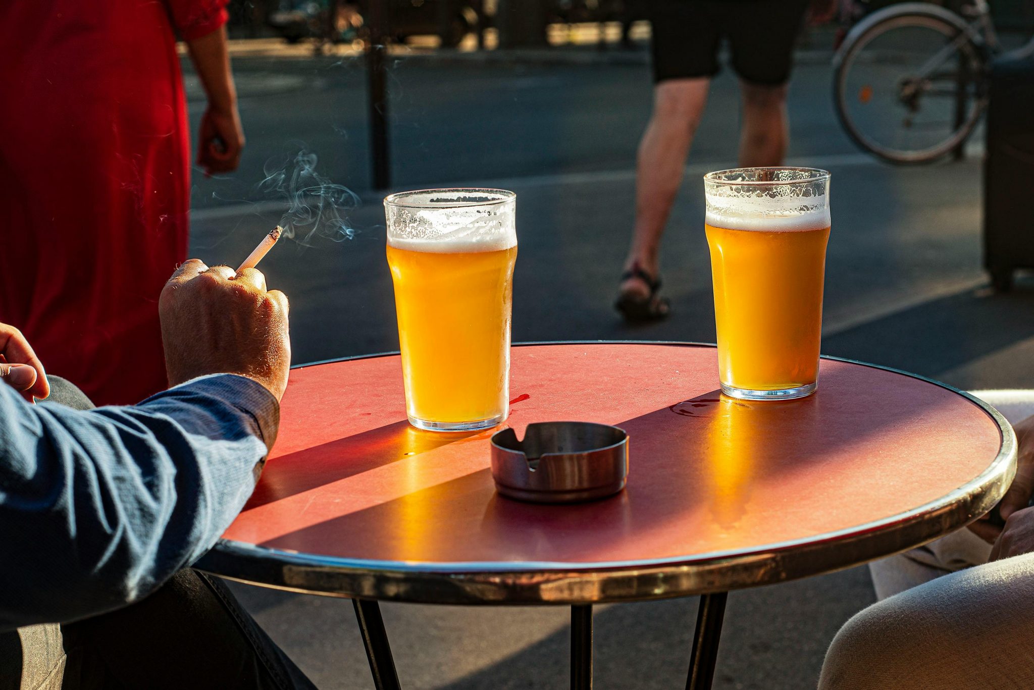 Close up to an outside terrace table with two full glasses of beer in France, a person